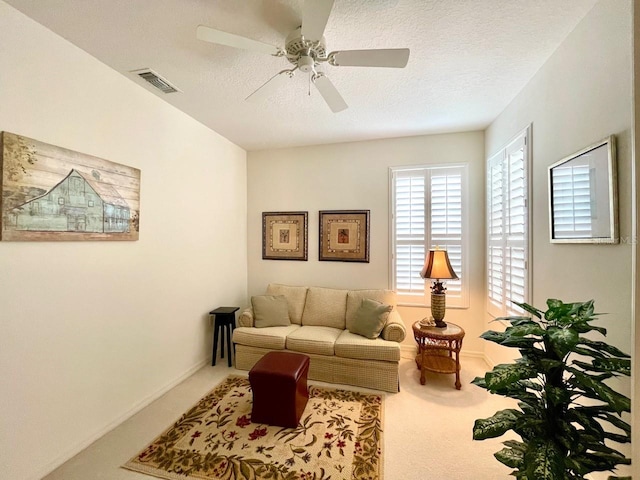 carpeted living room with ceiling fan and a textured ceiling