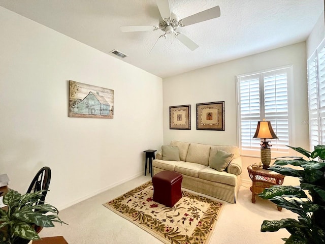 carpeted living room with ceiling fan and a textured ceiling