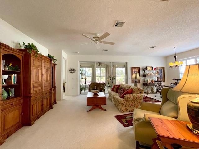 carpeted living room with ceiling fan with notable chandelier and a textured ceiling