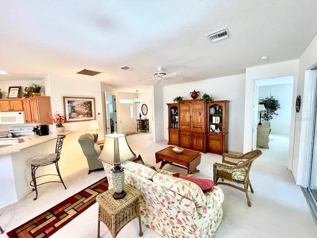 carpeted living room featuring ceiling fan and a textured ceiling