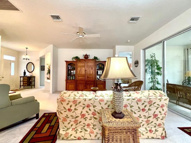 carpeted living room with ceiling fan and a textured ceiling