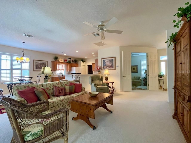 carpeted living room with ceiling fan with notable chandelier and a textured ceiling