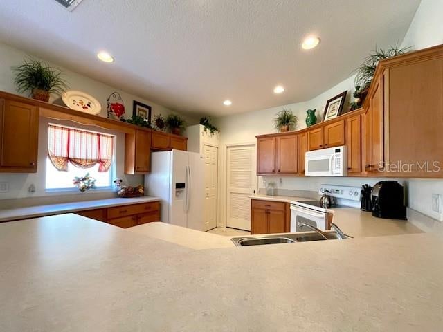 kitchen with sink, white appliances, and kitchen peninsula