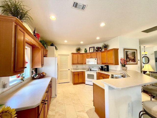 kitchen with white appliances, kitchen peninsula, sink, and a breakfast bar area