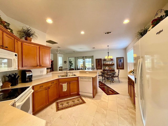 kitchen with sink, white appliances, ceiling fan with notable chandelier, decorative light fixtures, and kitchen peninsula