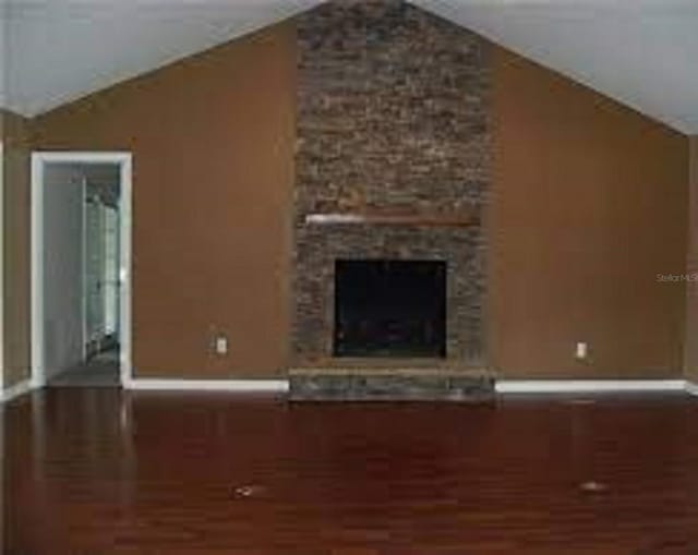 unfurnished living room with lofted ceiling, dark wood-type flooring, and a fireplace