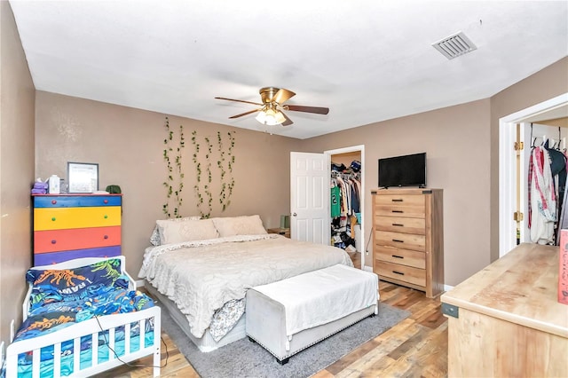 bedroom with a closet, a spacious closet, light hardwood / wood-style floors, and ceiling fan