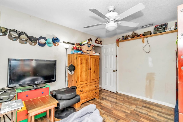 living area with a textured ceiling, ceiling fan, and dark hardwood / wood-style flooring