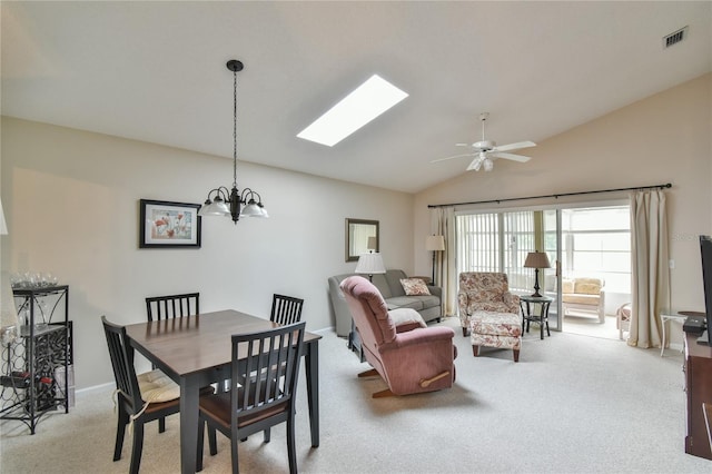 carpeted dining room with vaulted ceiling with skylight and ceiling fan with notable chandelier