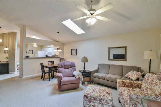 carpeted living room with lofted ceiling with skylight and ceiling fan with notable chandelier