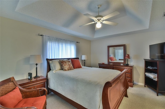 carpeted bedroom with a tray ceiling and ceiling fan