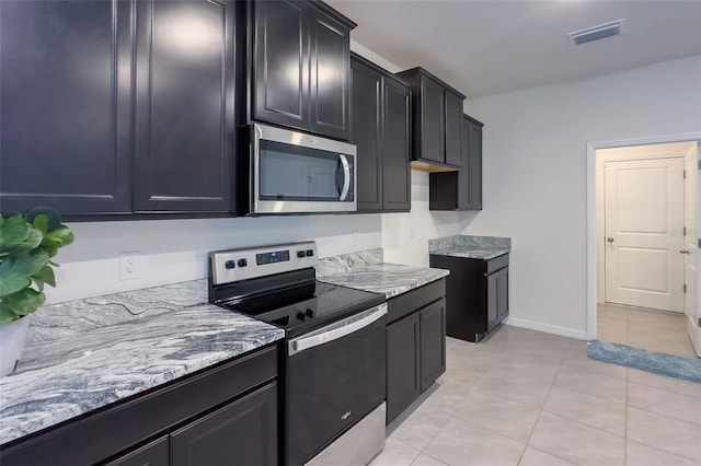 kitchen featuring stainless steel appliances, light stone countertops, and light tile floors