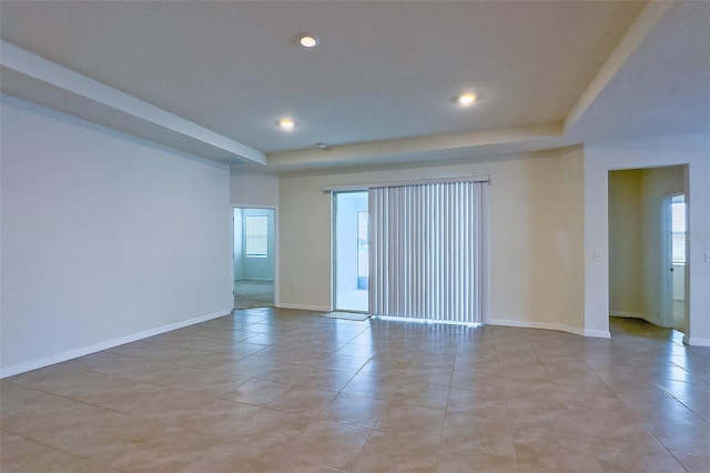 tiled empty room with a raised ceiling