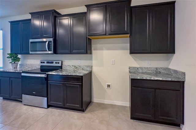 kitchen featuring light stone countertops, stainless steel appliances, and light tile flooring