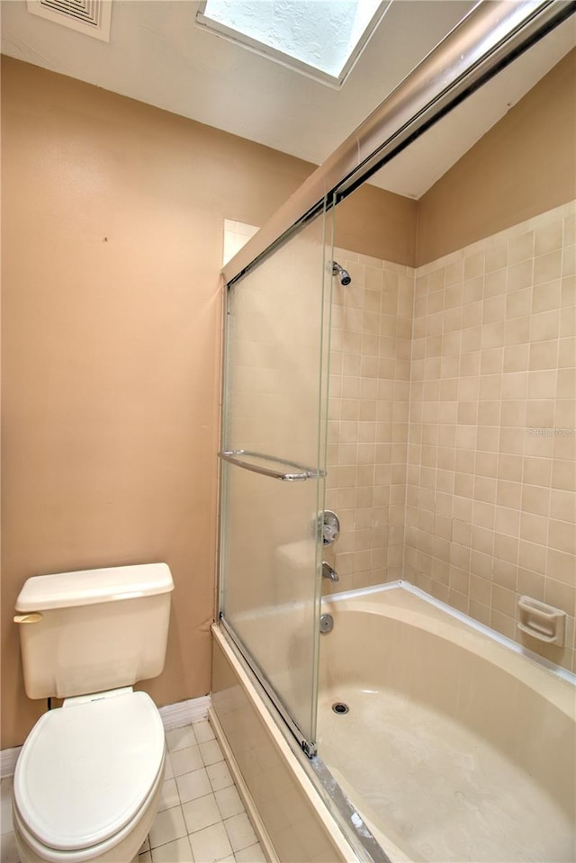 bathroom with a skylight, enclosed tub / shower combo, toilet, and tile patterned floors