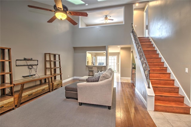 living room with high vaulted ceiling, ceiling fan, and light hardwood / wood-style flooring