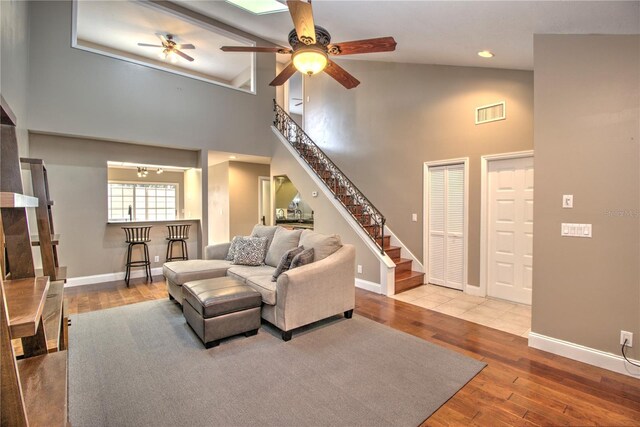 living room featuring light wood-type flooring, high vaulted ceiling, and ceiling fan