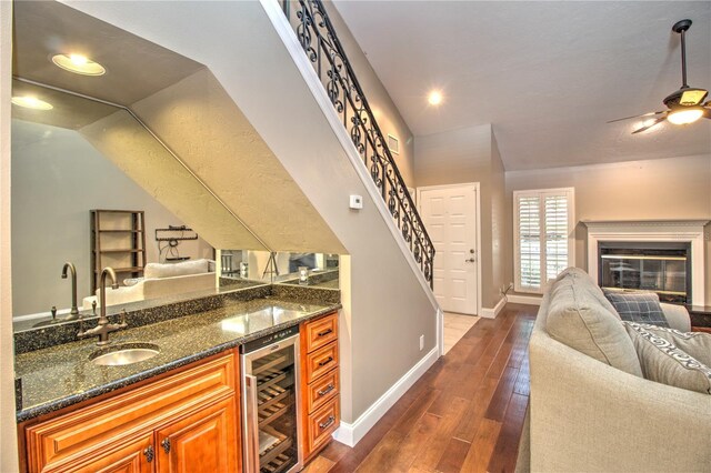 bar featuring dark stone countertops, dark wood-type flooring, wine cooler, and sink