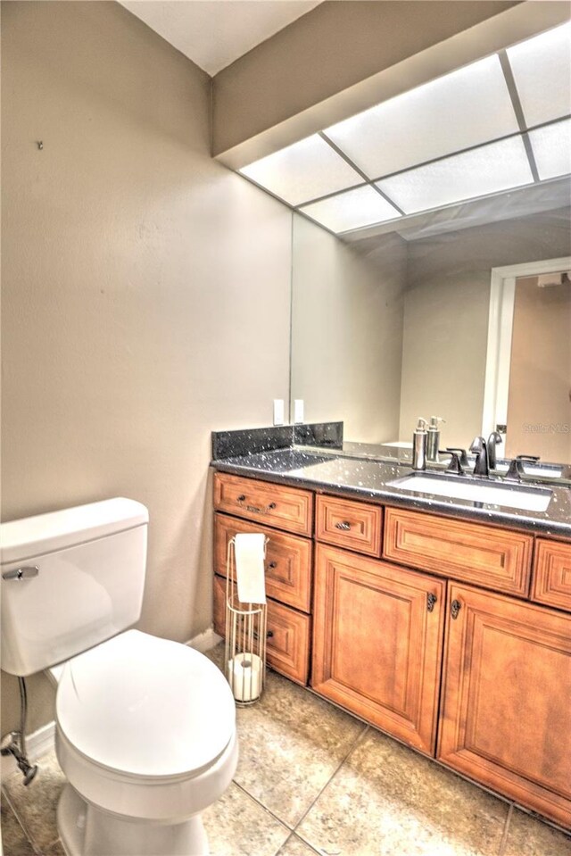 bathroom with tile patterned flooring, vanity, toilet, and a paneled ceiling