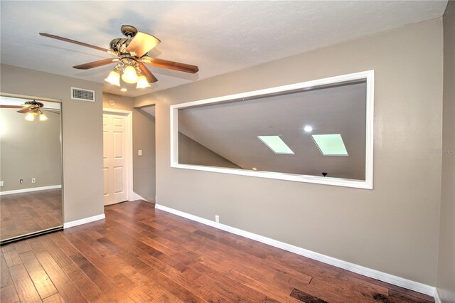 unfurnished room with hardwood / wood-style floors, ceiling fan, and a skylight