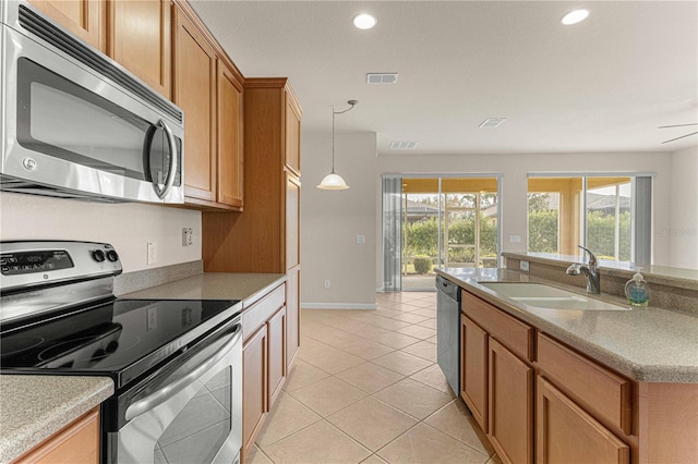 kitchen with appliances with stainless steel finishes, light tile patterned floors, pendant lighting, and sink