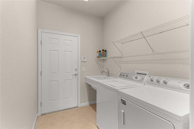 clothes washing area with light tile patterned flooring, sink, and independent washer and dryer