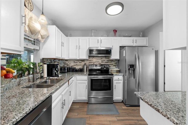 kitchen featuring pendant lighting, appliances with stainless steel finishes, backsplash, light stone counters, and sink