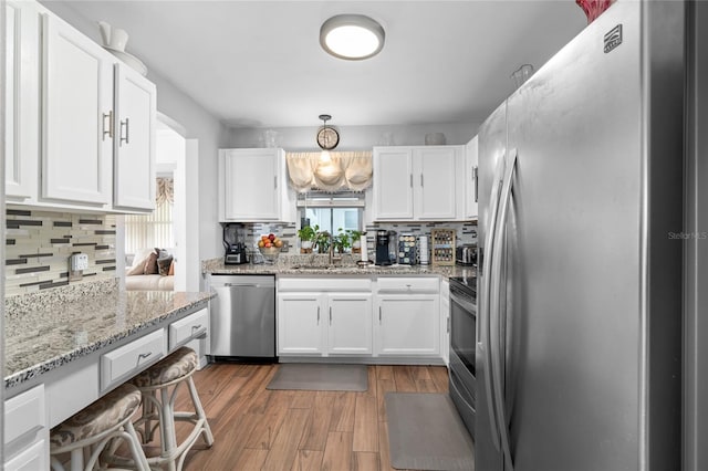 kitchen featuring white cabinets, backsplash, light hardwood / wood-style floors, and appliances with stainless steel finishes