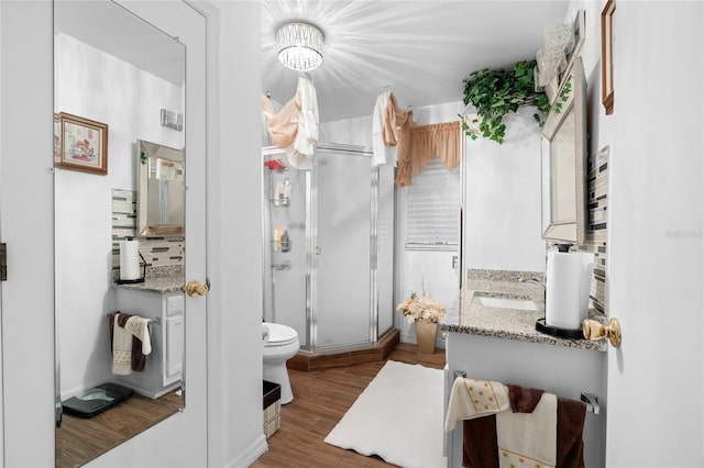 bathroom with toilet, a shower with shower door, backsplash, wood-type flooring, and vanity