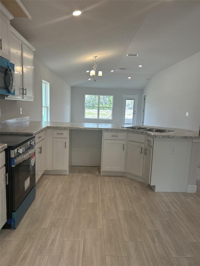 kitchen with stainless steel electric stove, white cabinetry, and lofted ceiling