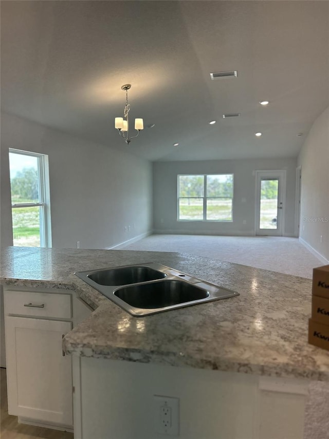 kitchen with white cabinetry, a healthy amount of sunlight, vaulted ceiling, and decorative light fixtures