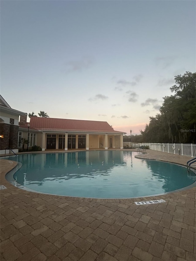 pool at dusk featuring a patio area