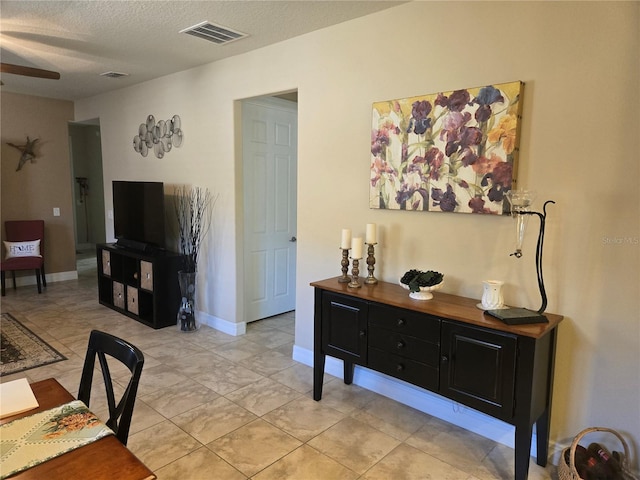 living room with light tile floors, a textured ceiling, and ceiling fan