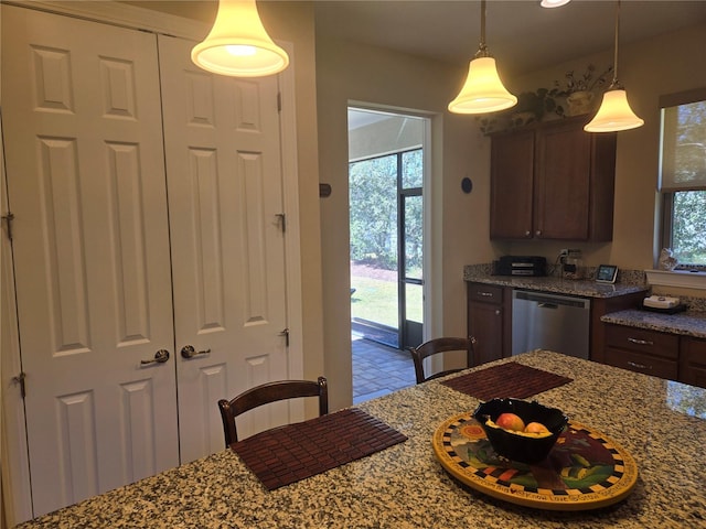 kitchen with plenty of natural light, decorative light fixtures, stone countertops, and stainless steel dishwasher