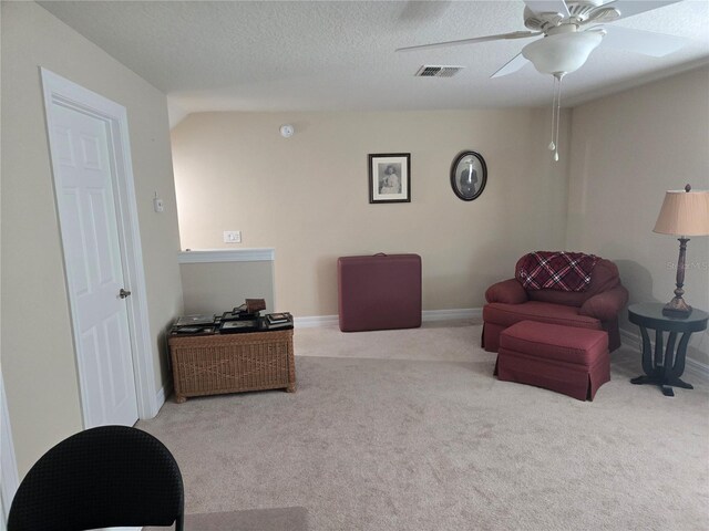 living area featuring a textured ceiling, ceiling fan, and light colored carpet