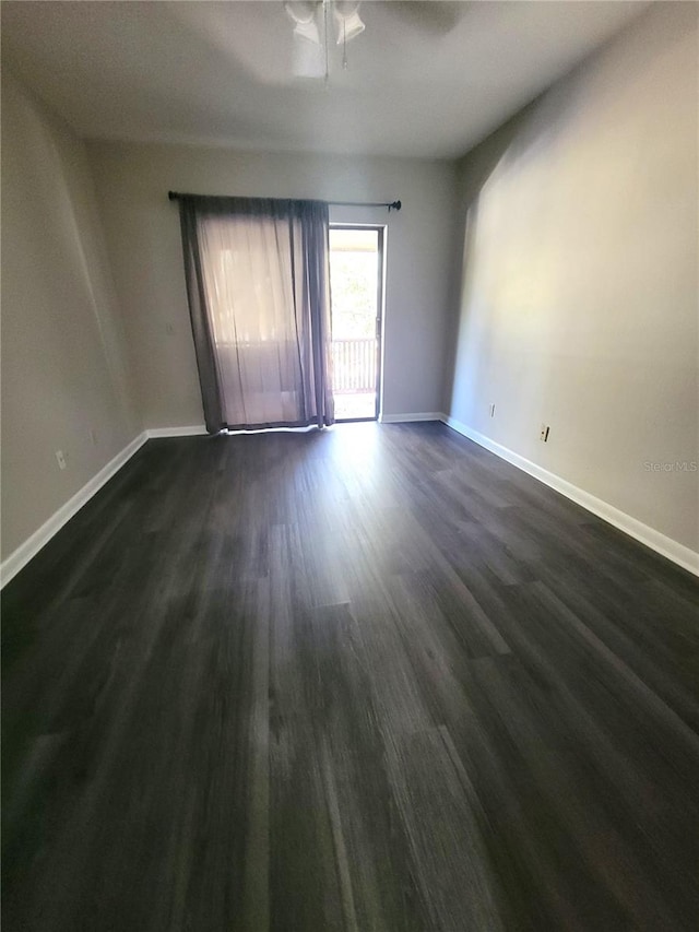 spare room featuring dark wood finished floors, baseboards, and ceiling fan