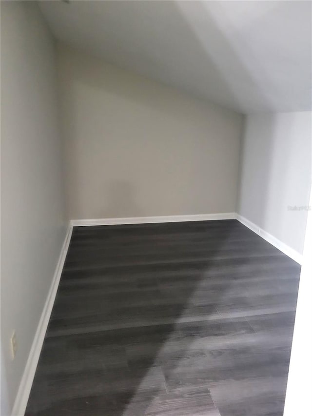 bonus room with dark wood finished floors and baseboards