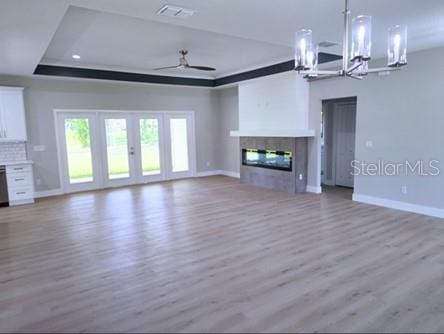 unfurnished living room with french doors, hardwood / wood-style floors, ceiling fan, and a raised ceiling