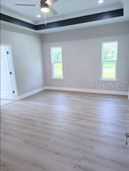 spare room featuring plenty of natural light, hardwood / wood-style flooring, and a raised ceiling