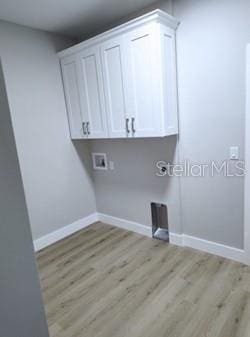 clothes washing area with cabinets, washer hookup, and light hardwood / wood-style floors