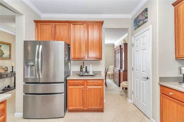 kitchen with light tile floors, crown molding, and stainless steel fridge