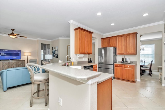 kitchen featuring sink, light tile floors, stainless steel appliances, a kitchen bar, and ceiling fan with notable chandelier