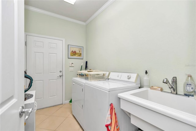 laundry area featuring washer and clothes dryer, crown molding, light tile floors, and sink