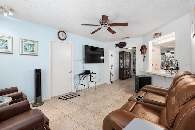 living room with a textured ceiling, light tile flooring, and ceiling fan