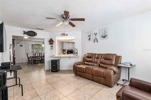 living room with light tile floors, ceiling fan, and a textured ceiling