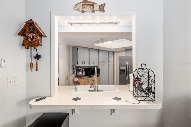 kitchen featuring gray cabinetry, tile countertops, sink, and stainless steel appliances