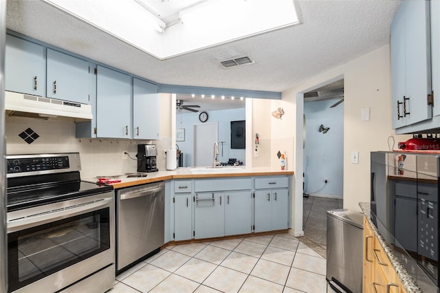 kitchen featuring backsplash, appliances with stainless steel finishes, light tile floors, and sink