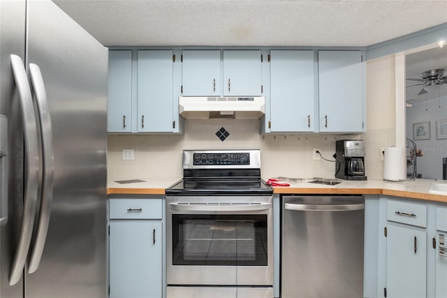 kitchen featuring blue cabinetry, ceiling fan, a textured ceiling, appliances with stainless steel finishes, and backsplash