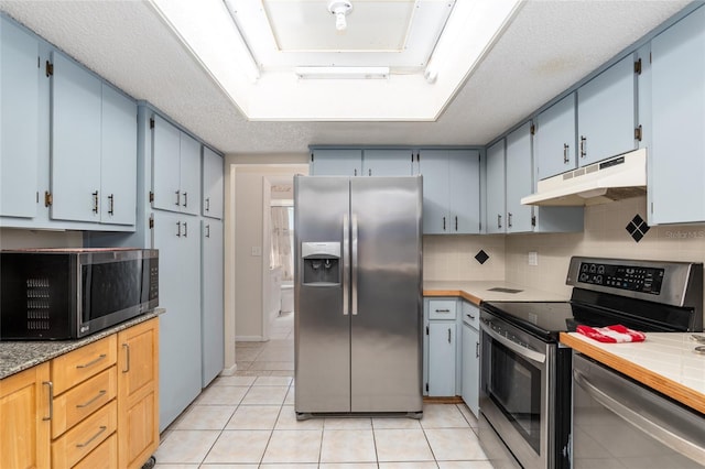 kitchen with light tile flooring, backsplash, a textured ceiling, and appliances with stainless steel finishes