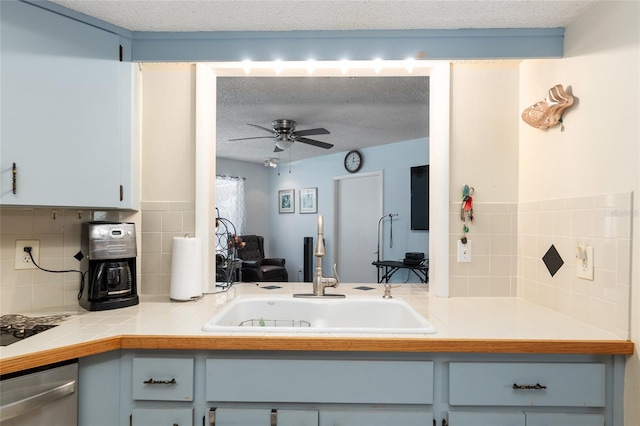 kitchen featuring stainless steel dishwasher, ceiling fan, a textured ceiling, and sink